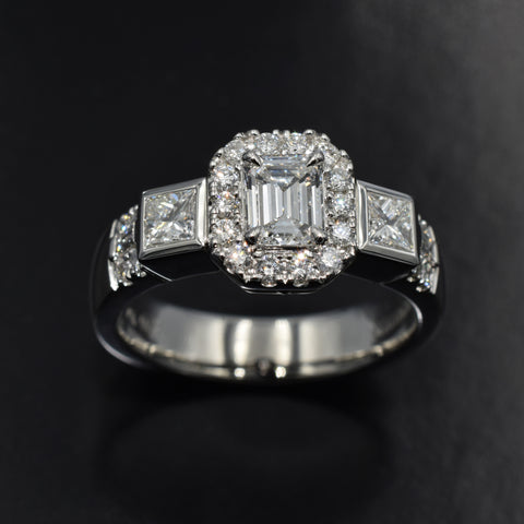Platinum halo trilogy ring with emerald cut diamond center and princess cut sides